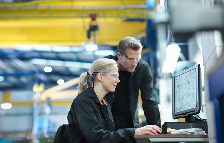 Two manufacturing professionals looking at a computer screen.