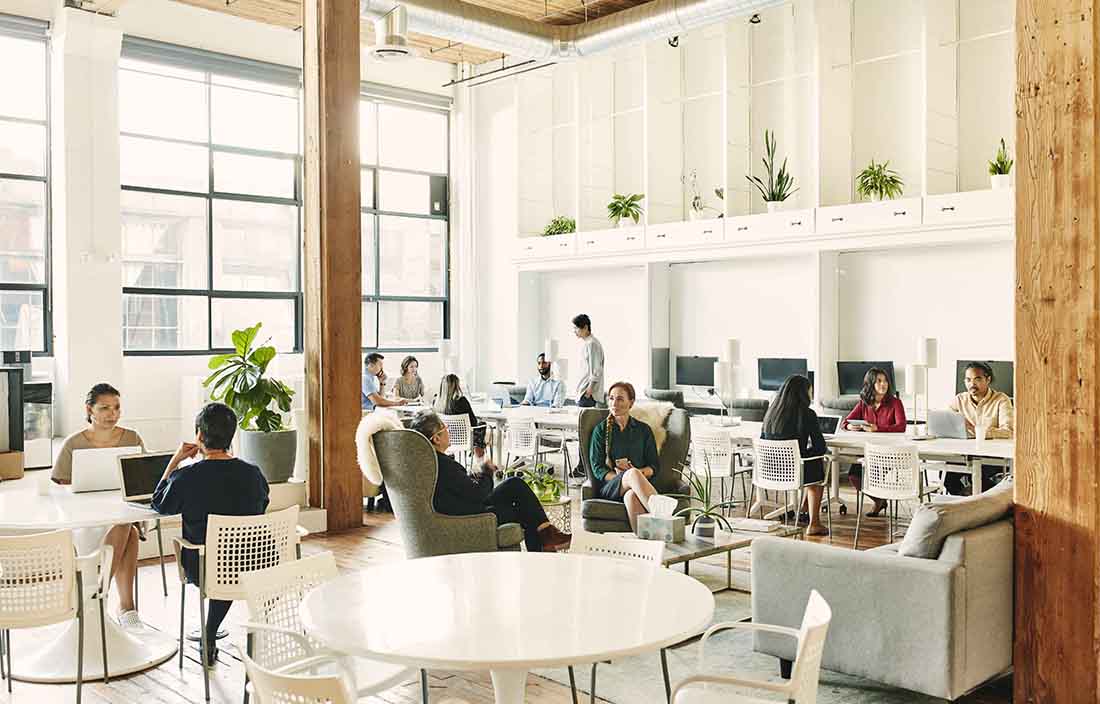 Team of business professionals sitting in a modern office at their desks in an open floor plan.