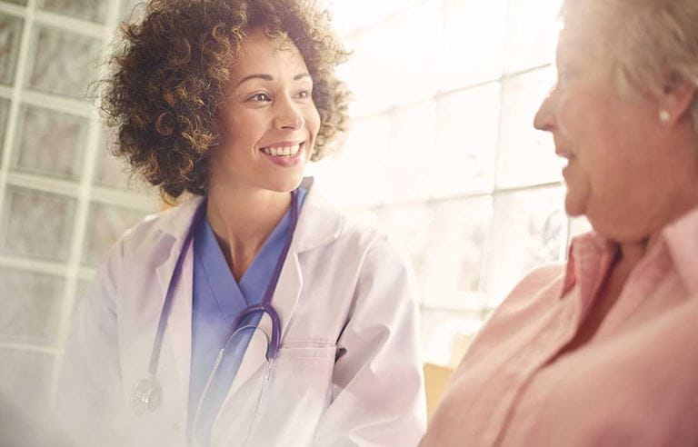 Doctor sitting and smiling while talking to an elderly patient.