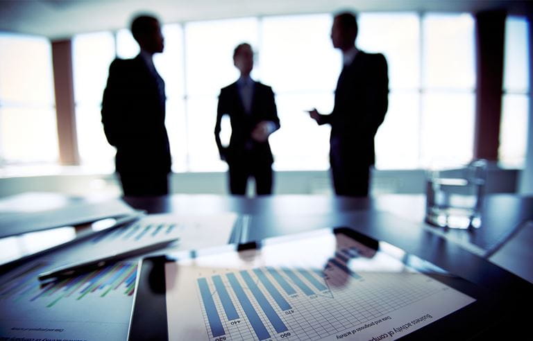 Three silhouettes of business professionals in an office.