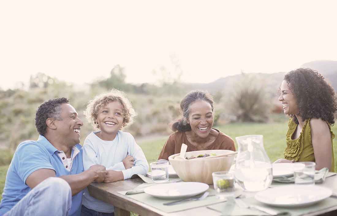 Family having a meal together outside at a picnic table.