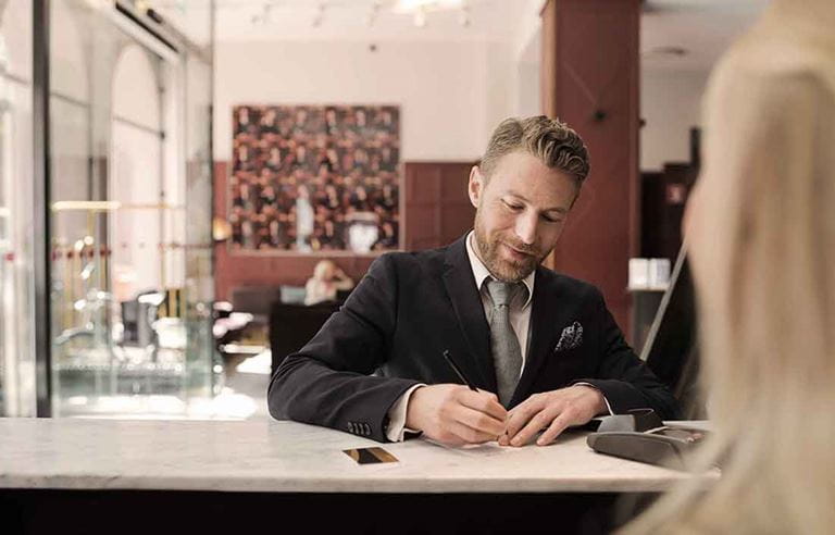 Man in a suit signing paperwork.