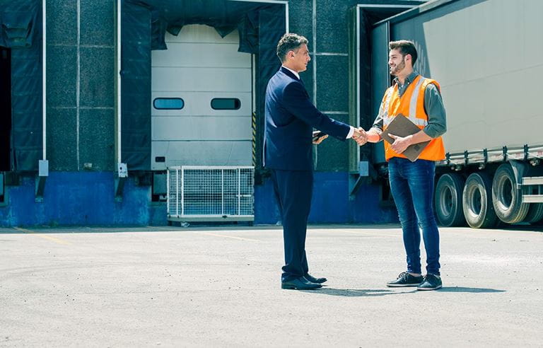 Business professional shaking hands with a shipping and receiving employee.