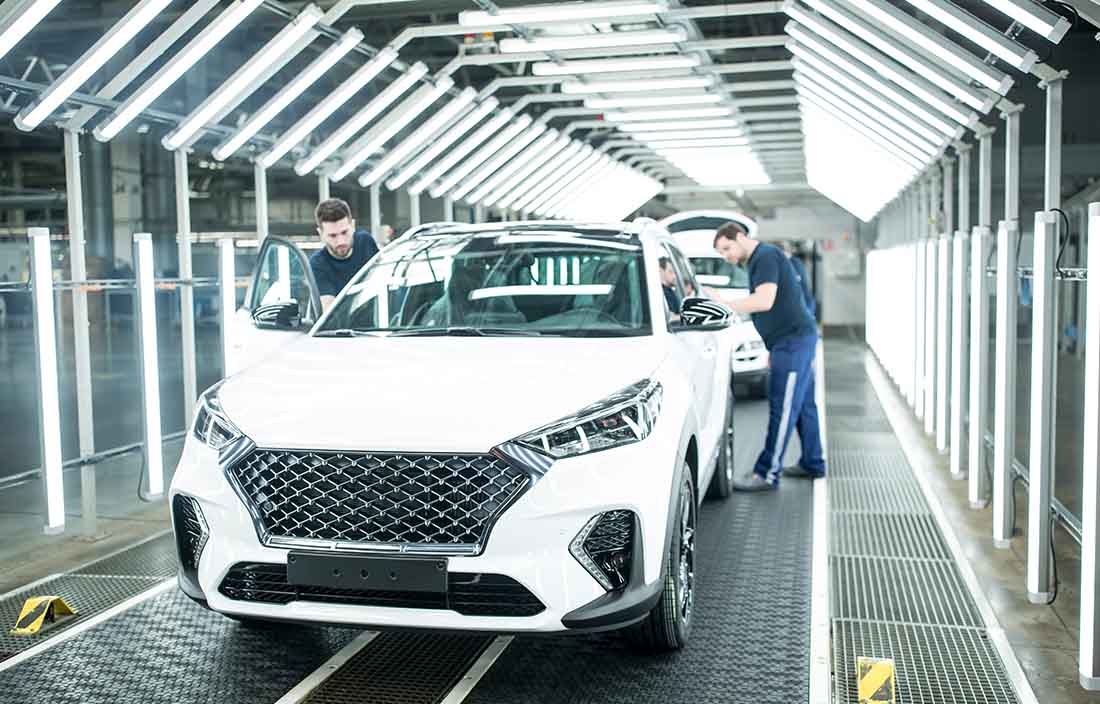 Factory workers inspecting a new car.