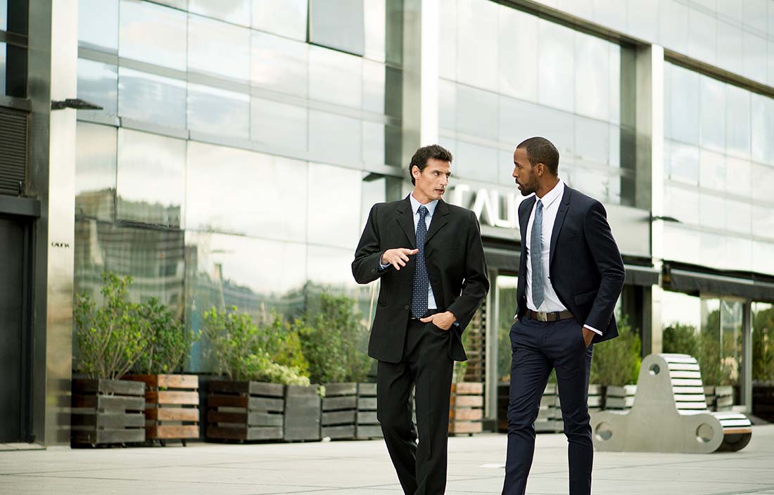 Two business professionals having a discussion on the sidewalk.