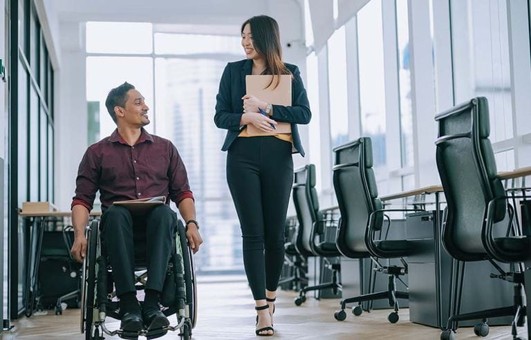 Two colleagues laughing and talking in workplace.