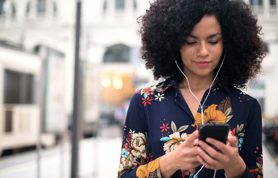 Person in floral shirt listening to podcast on their phone.