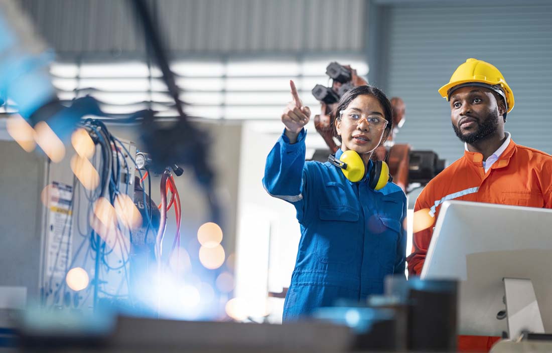 Manufacturing workers standing and talking with one another. 