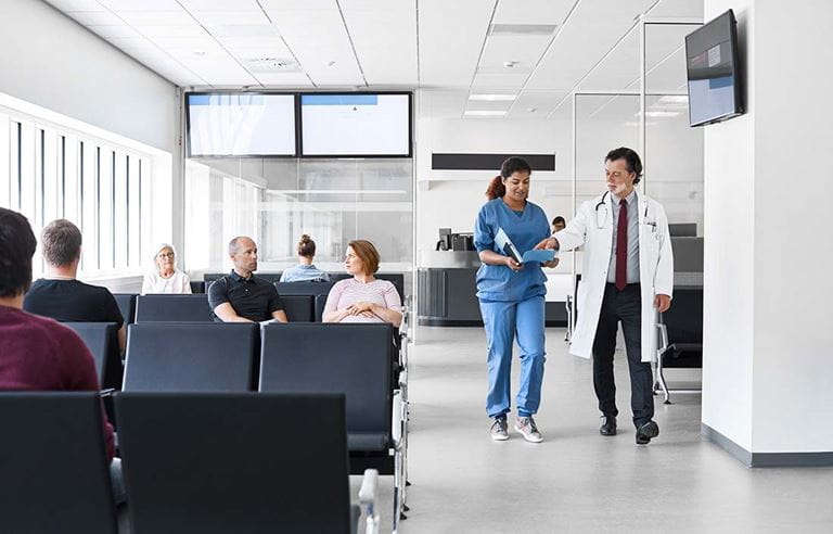 Confident doctor and nurse walking in waiting room of urgent care clinic.