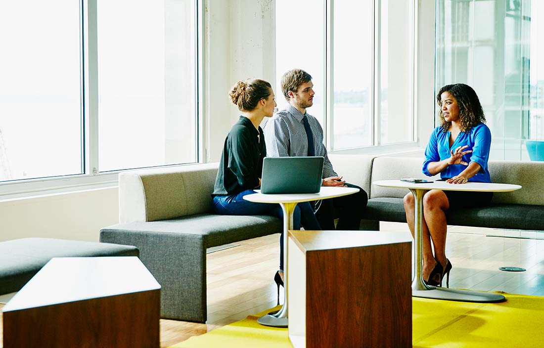 Two people discussing their financial goals with their financial advisor across from them.