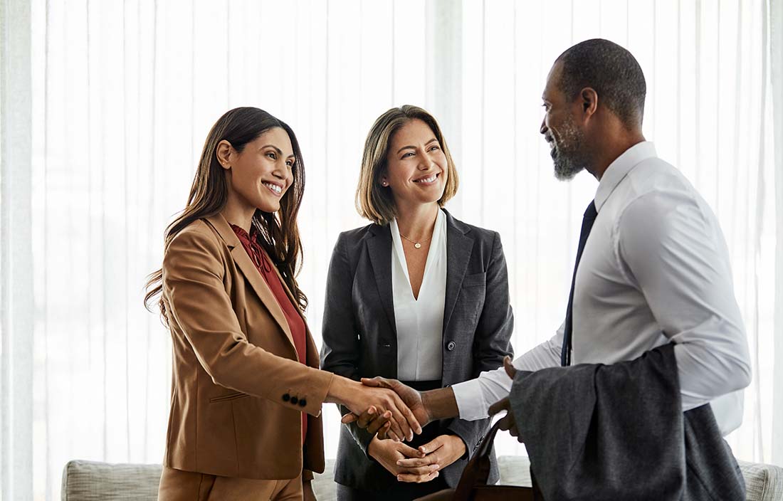 Business professionals shaking hands and discussing employer-sponsored health clinics.