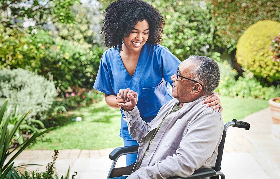 Nurse smiling and helping senior man at SNF facility.