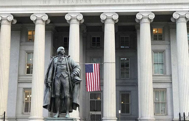 Front of government building with U.S. flag and statue.