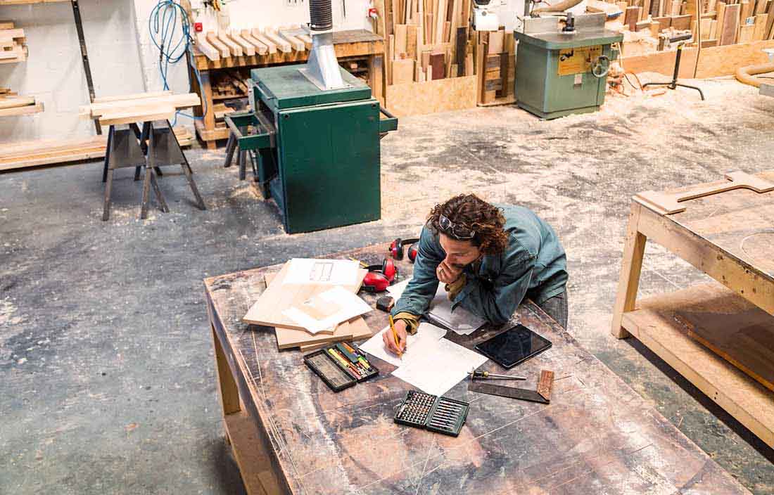 Craftsperson sketching out designs in their shop.