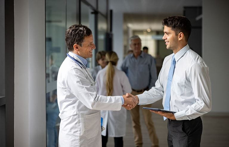 Healthcare leader shaking hands with restructuring consultant.