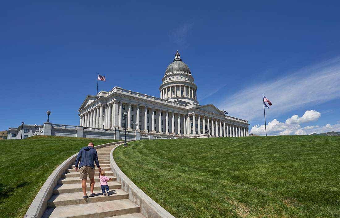 Parent and child walking up steps towards U.S. Capitol. 