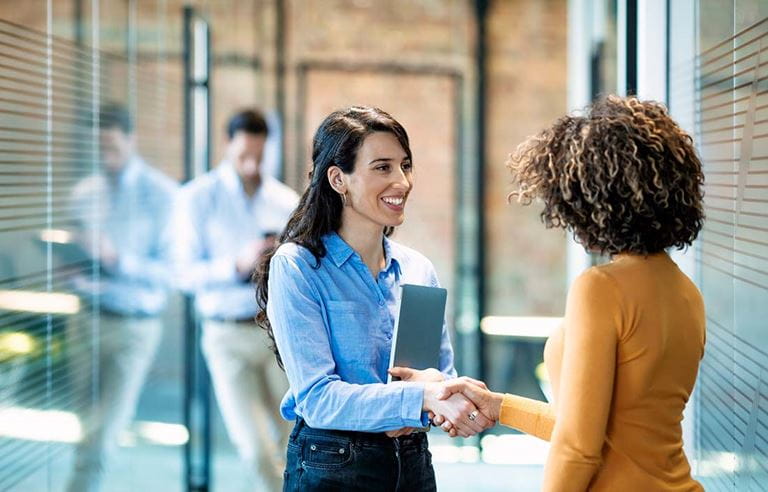 Two business professionals shaking hands and discussing the Section 1202 QSBS exemption benefit.