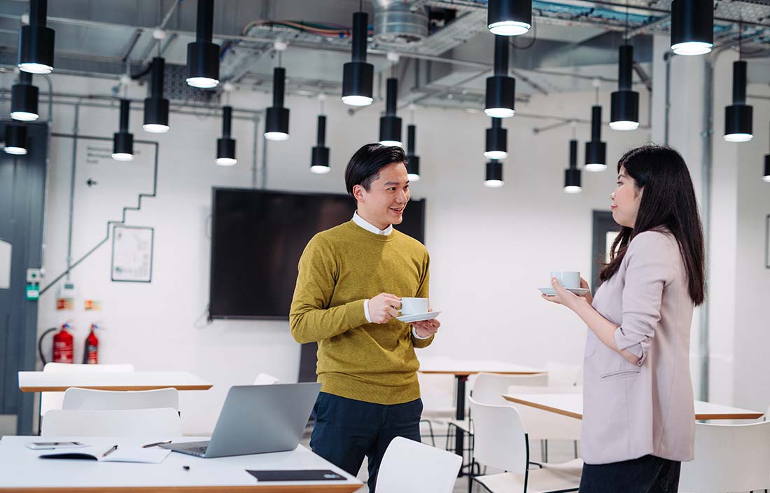 Two forensic accountants standing in a modern office and discussing how to identify and report fraud.