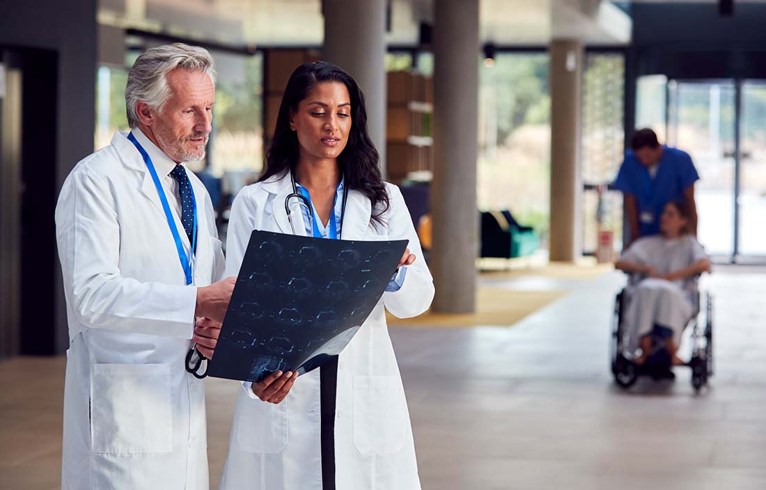 Two doctors in a hospital looking at patient charts.