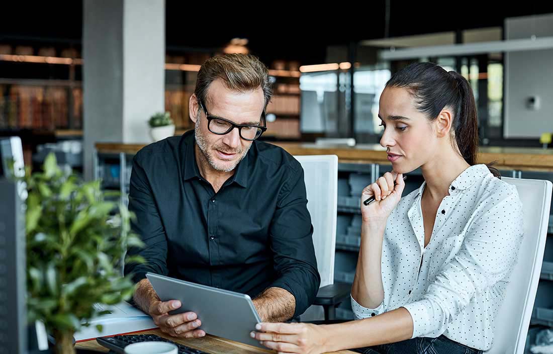 Financial advisor showing charts to their client on a tablet computer.