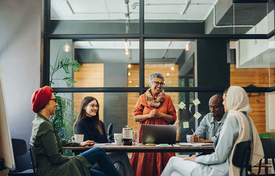 Group of coworkers gathered around in a modern conference room.