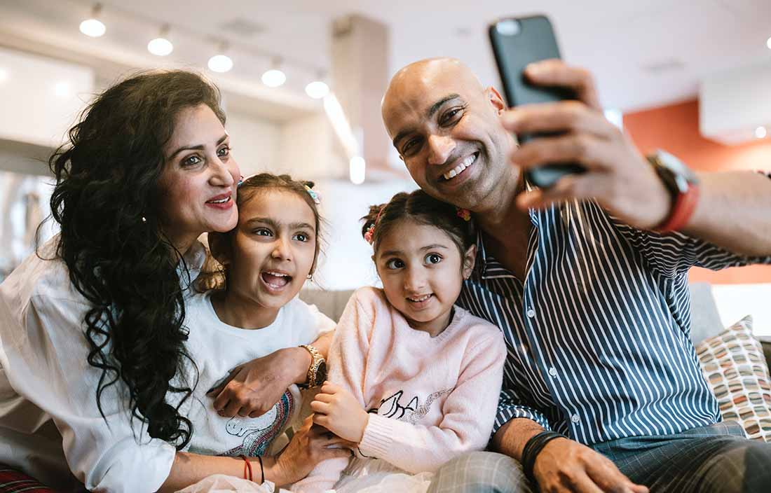 Parents and their children smiling and taking a selfie.