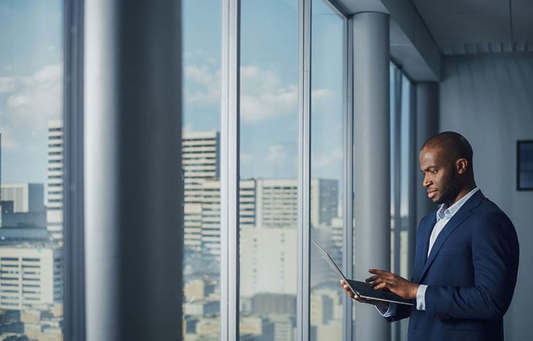 Business professional in a modern office building looking at their laptop.