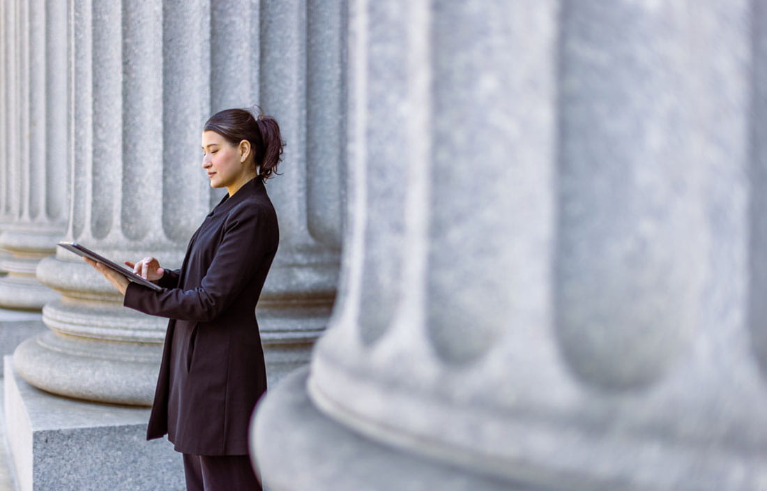 Business professional standing against a government building's pillar.