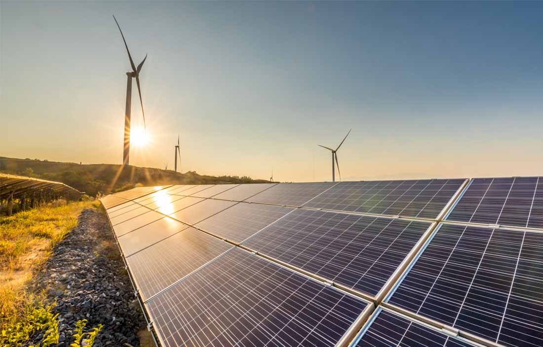 Solar panels and wind turbines at dusk.