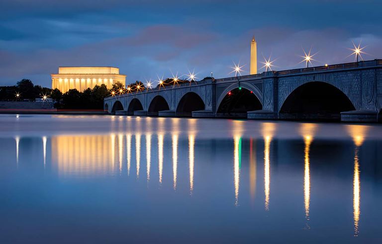 View of government building reflected in water.