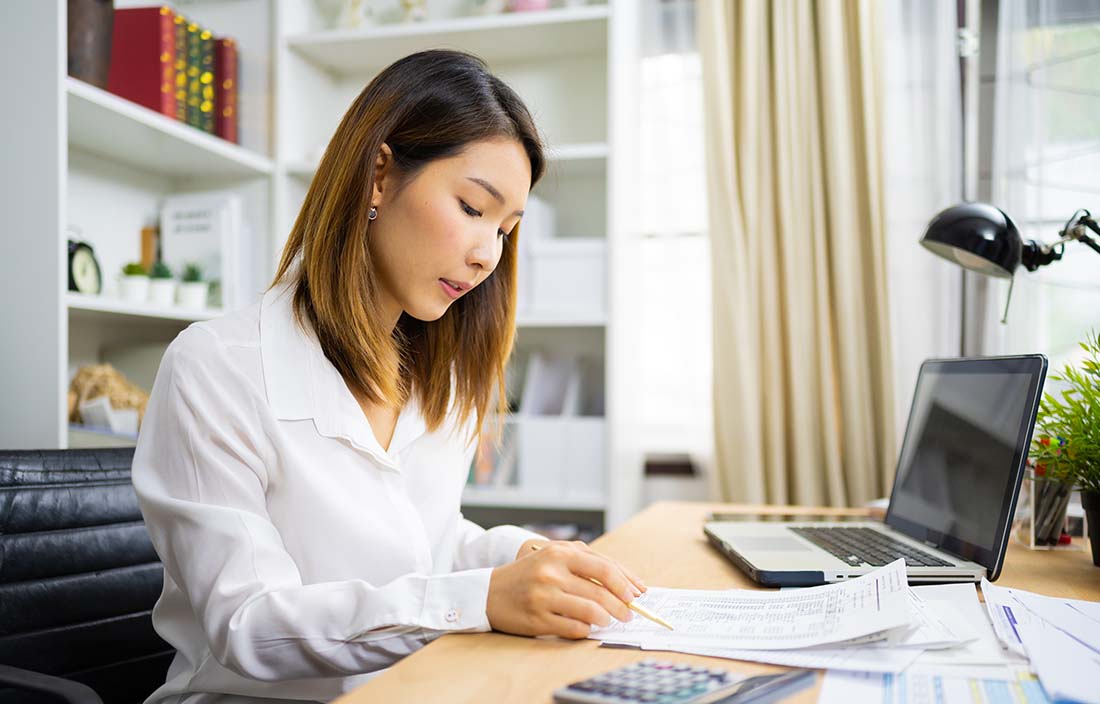 Business professional reviewing documents at their desk.