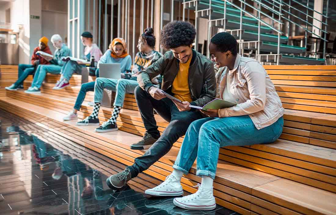 Students sitting on wooden bleachers working on homework together.