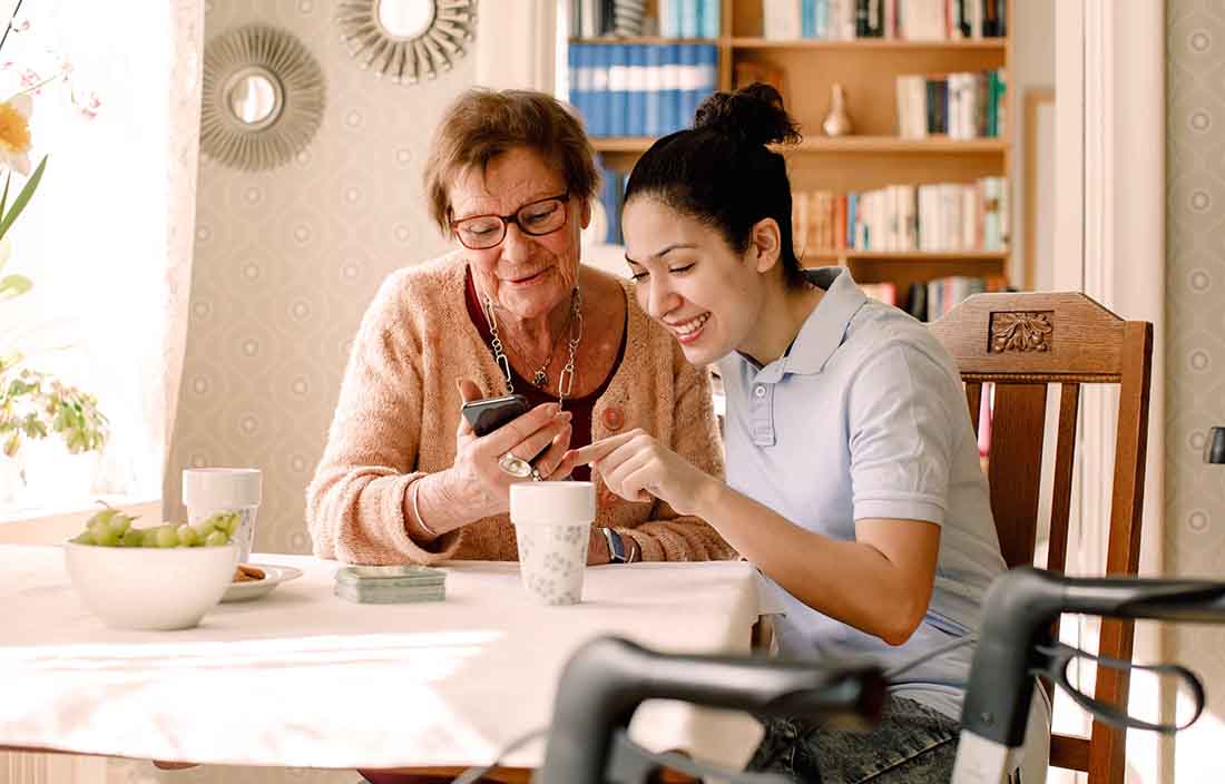 Elderly senior citizen receiving help with their cell phone device.