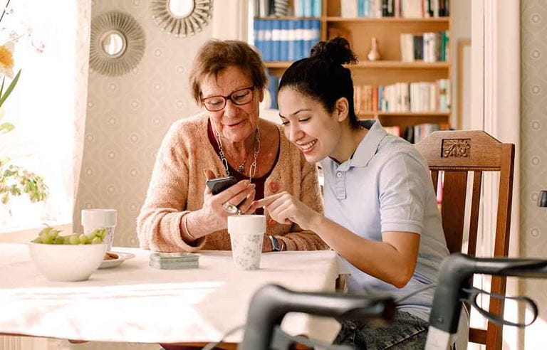 Elderly senior citizen receiving help with their cell phone device.