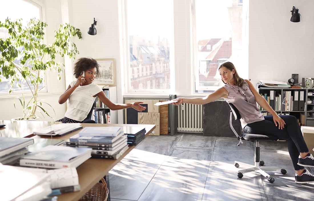 Two business professionals passing paperwork to one another.