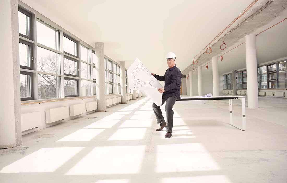 Construction worker leaning on a table looking at blueprint plans.