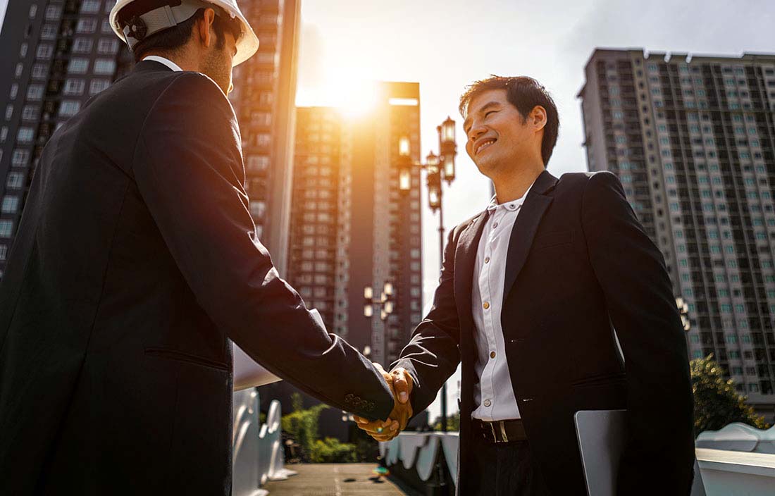 Construction workers shaking hands at a construction site.