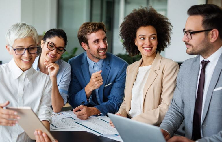 Group of business professionals smiling and talking to each other.