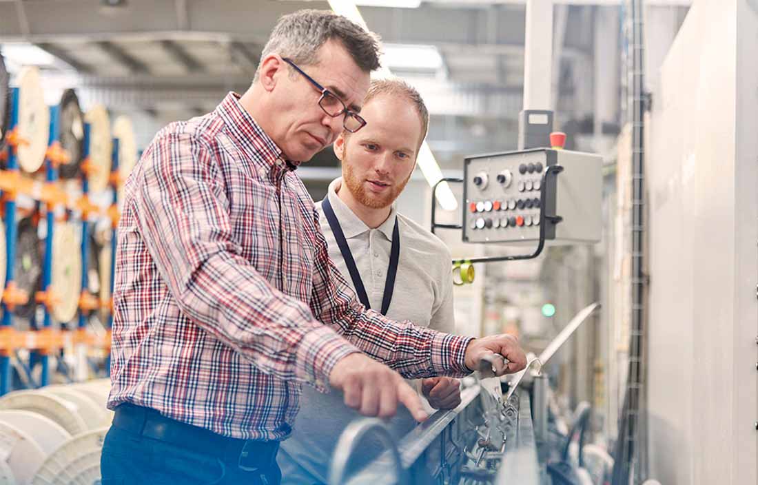 Two factory workers inspecting factory machine