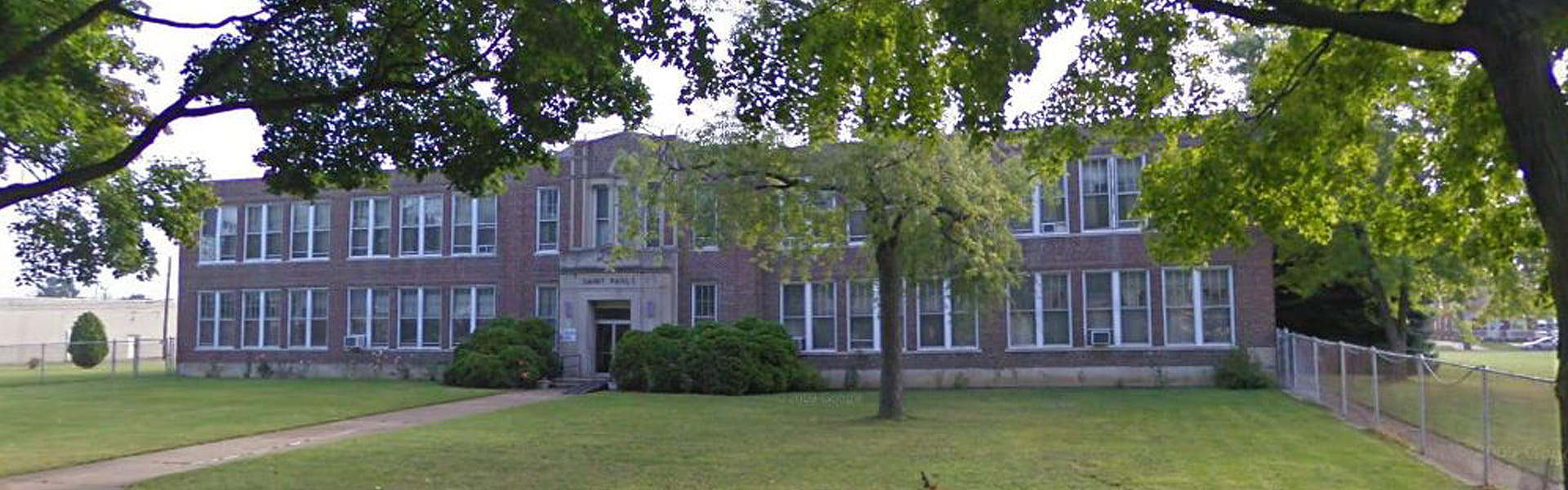 View of Pious Society of St. Paul school building through branches of a tree.