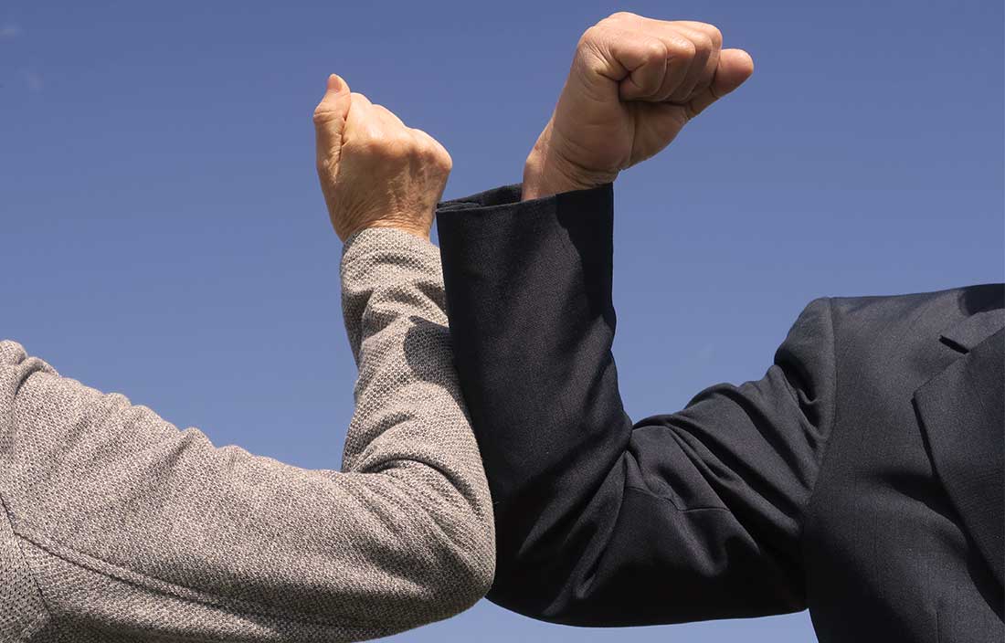 Two seniors "high-fiving" with their arms to avoid hand contact because of COVID