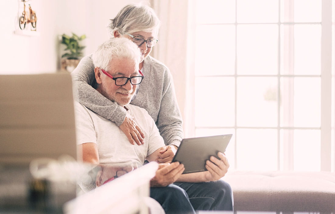 Senior couple in their modern home, looking at a tablet and smiling