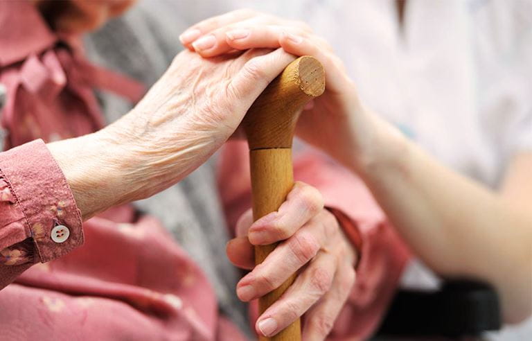 Close up of senior woman's hands on a cane