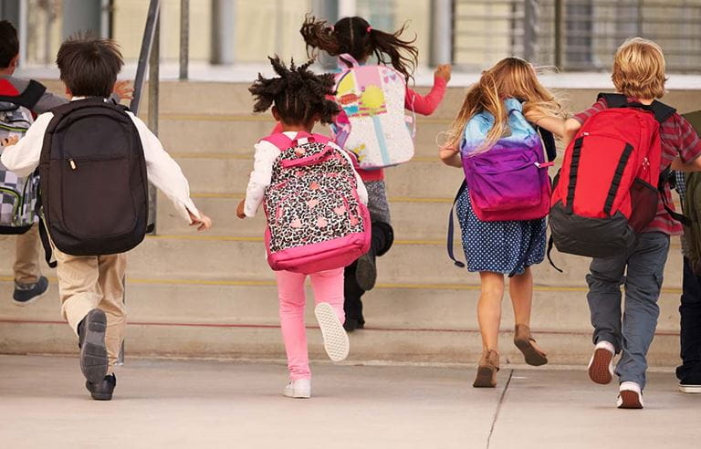 Image of elementary students sunning toward a school building