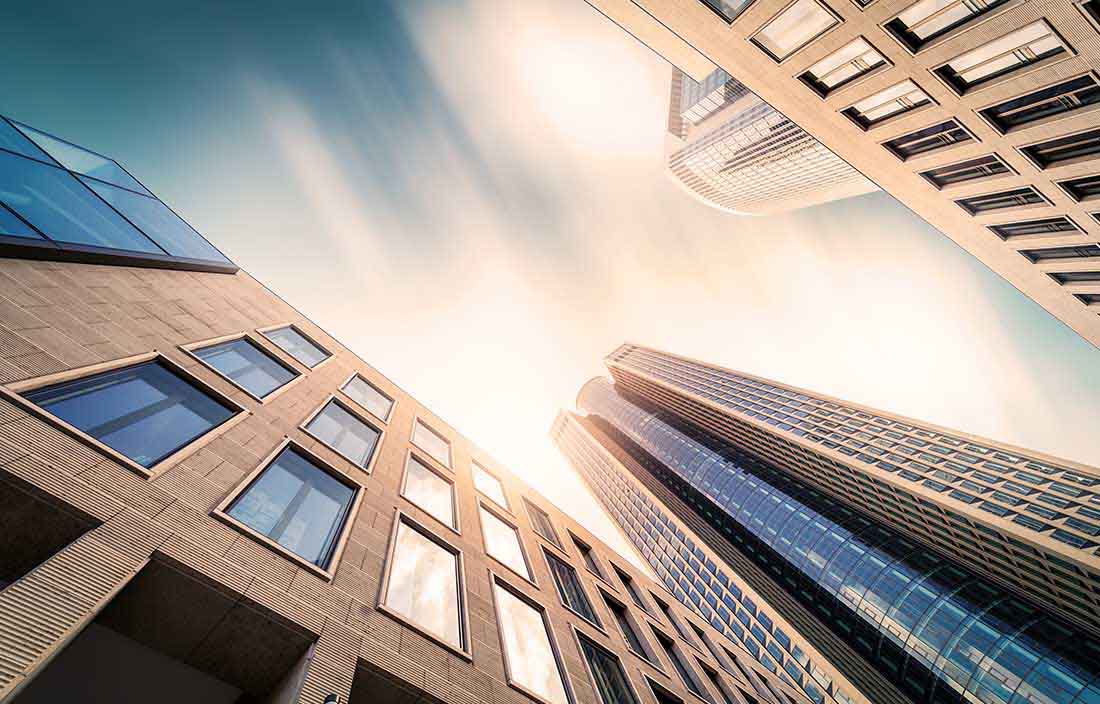 Photo of skyscrapers against blue sky, looking up from the ground