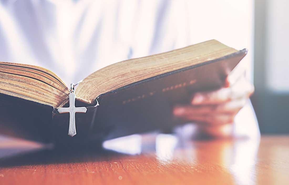 Close up of a person reading a bible at a table