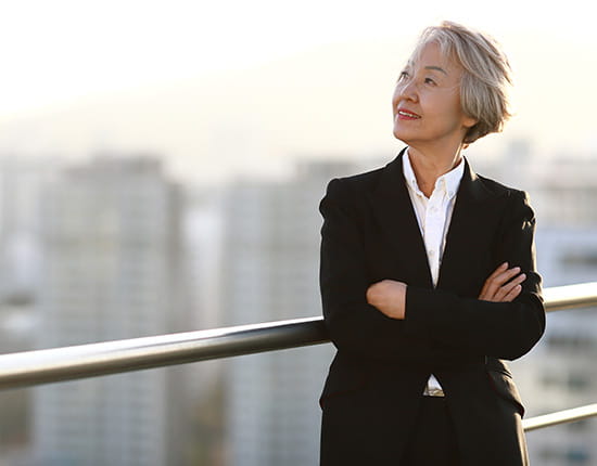 Business professional standing on a rooftop looking at the sunrise smiling.