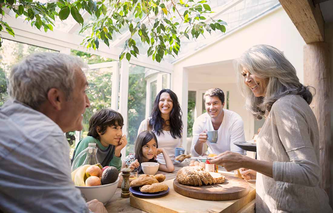 Family outside at a table with woman serving bread.