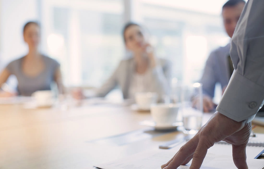 Image of a conference room meeting with four people sitting around a table.