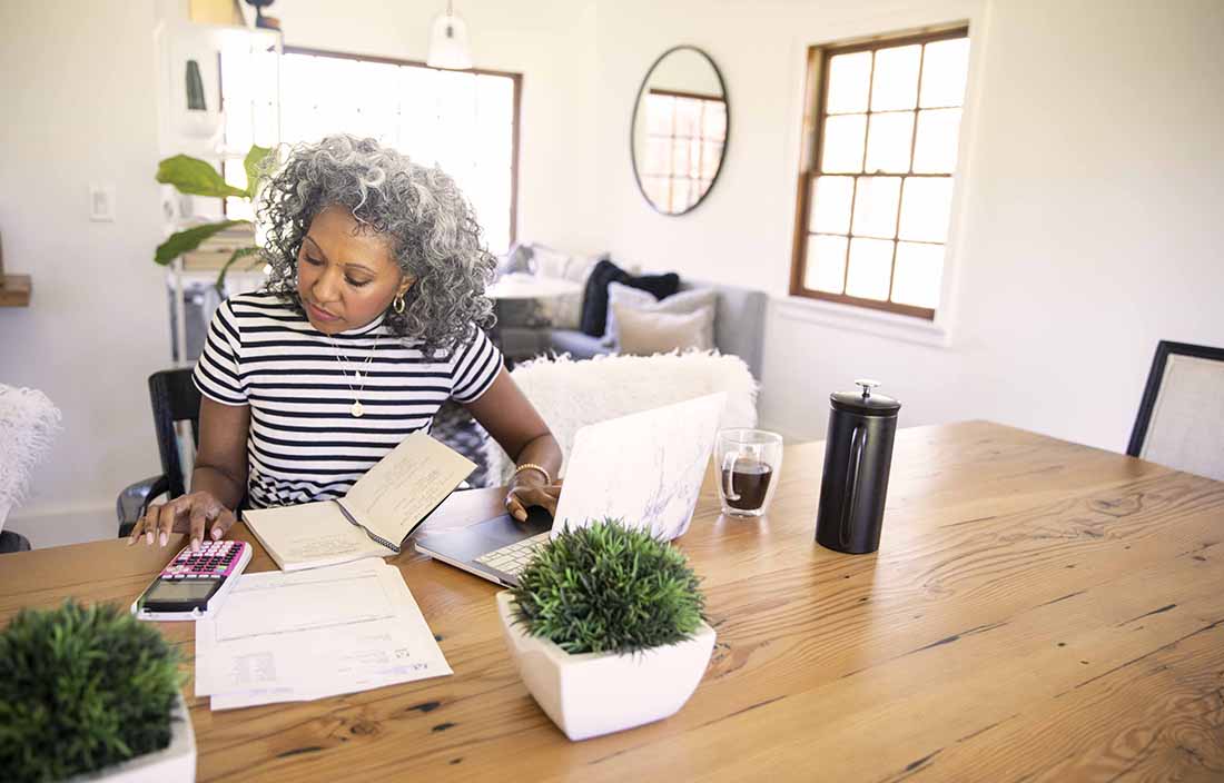 Middle-aged woman sitting at table reviewing tax documents.